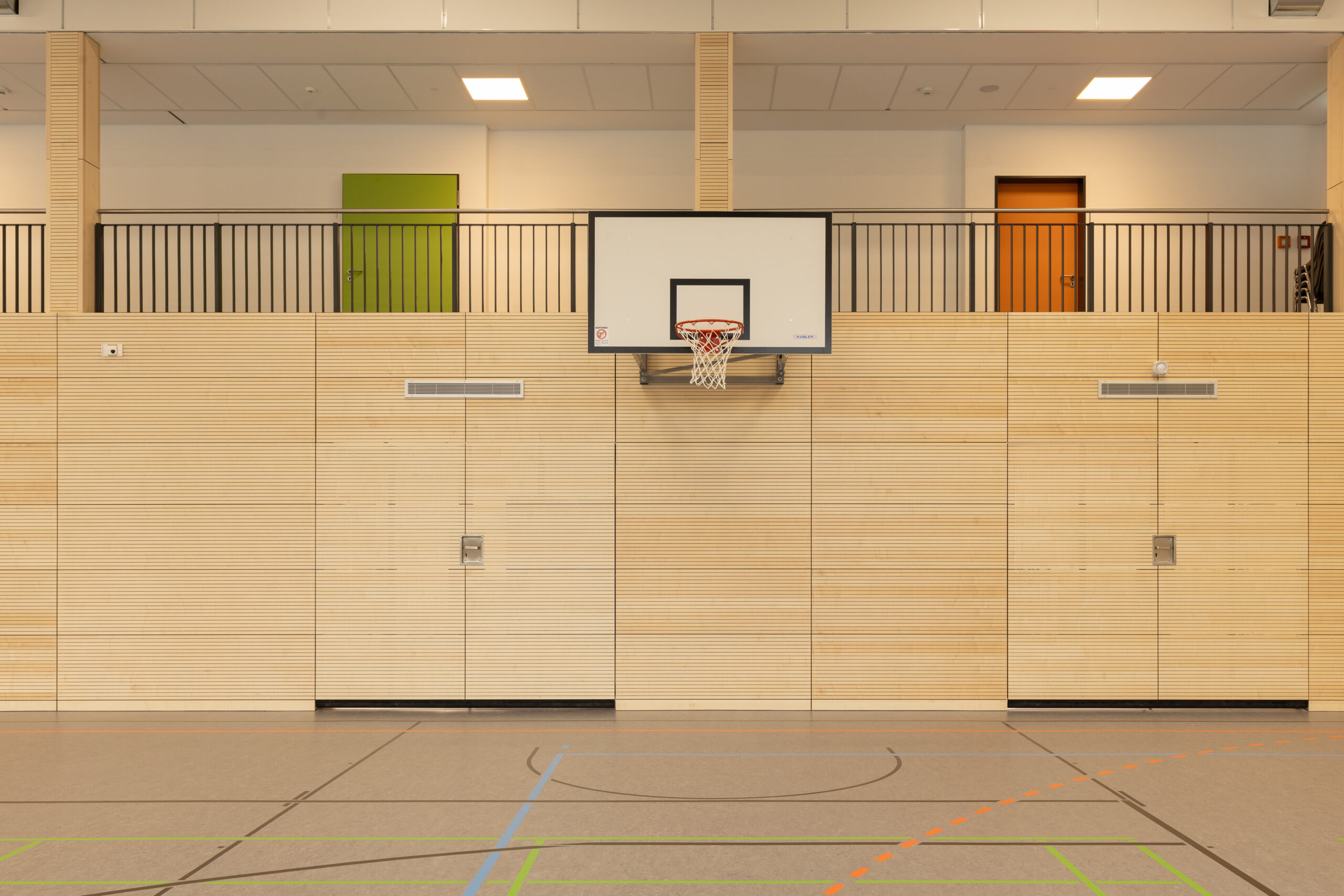 Gymnasium Neubau Sporthalle mit Basketballkorb und Holzverkleidung, geplant und umgesetzt durch das Architekturbüro Die Planschmiede