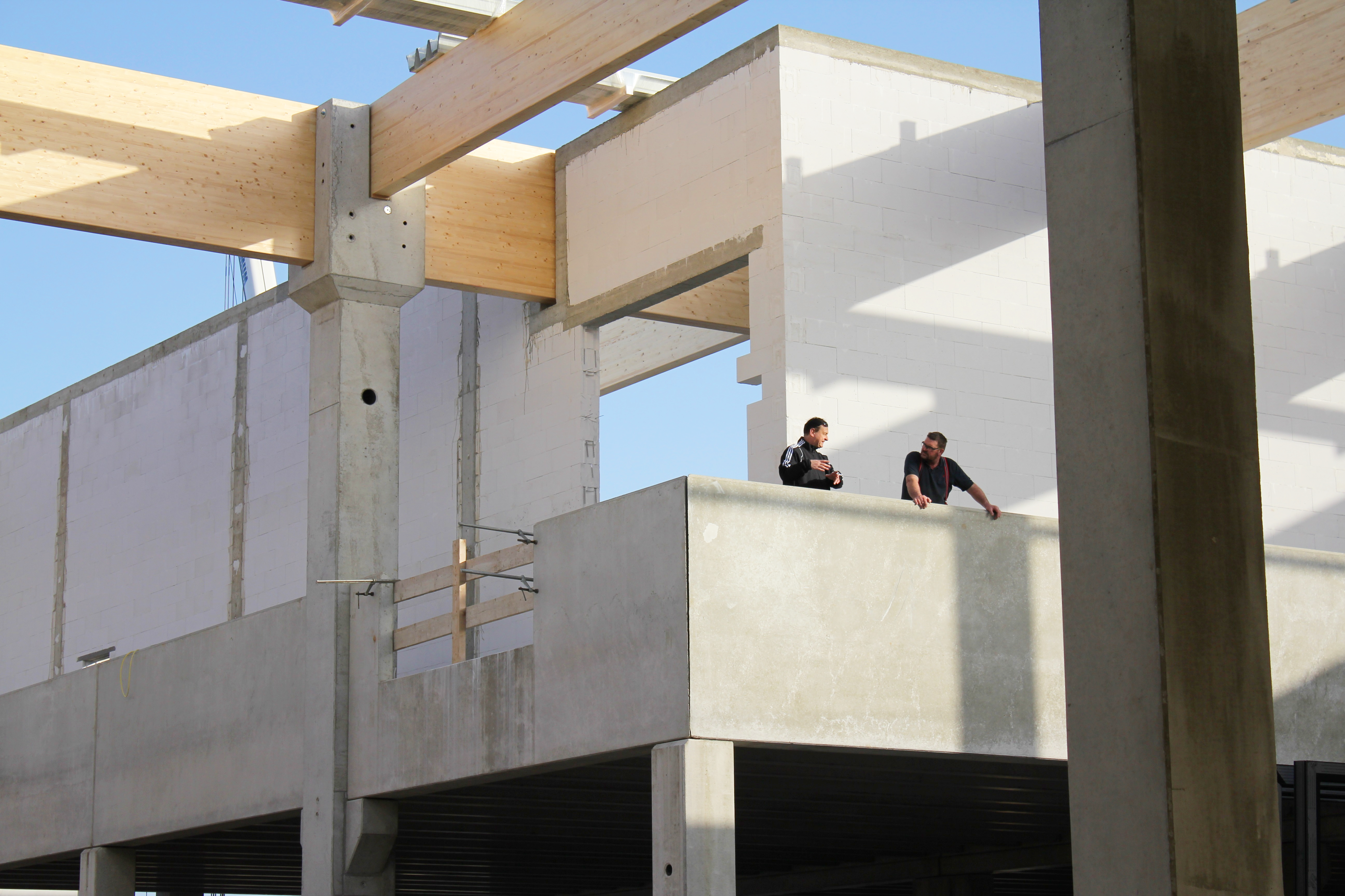 Zwei Mitarbeiter testen die Statik der Holz- und Betonpfeile bei einem Neubau, Tragwerksplanung nach HOAI durch das Architekturbüro Die Planschmiede